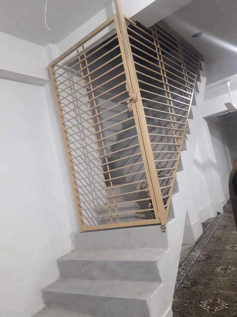 Unique staircase with a slanted wooden railing and concrete steps in a modern interior.