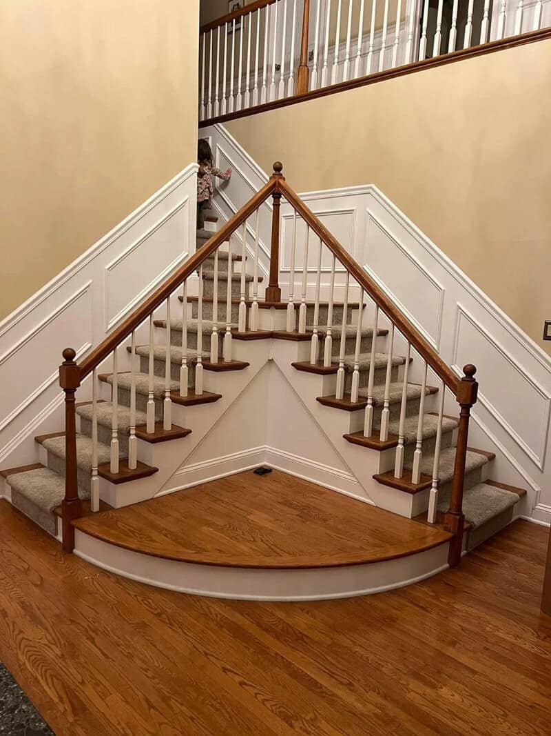 Unique staircase with a curved wooden platform and two sets of stairs meeting at the top.