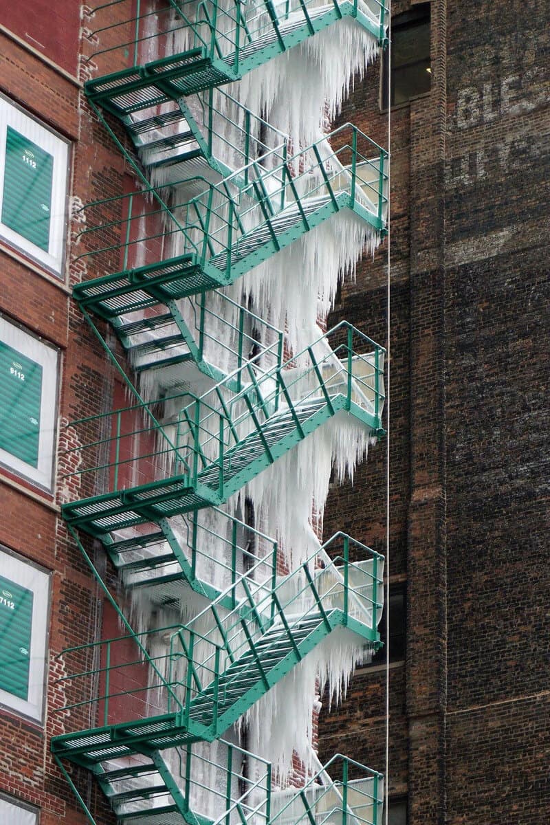 Fire escape covered in icicles on a brick building.
