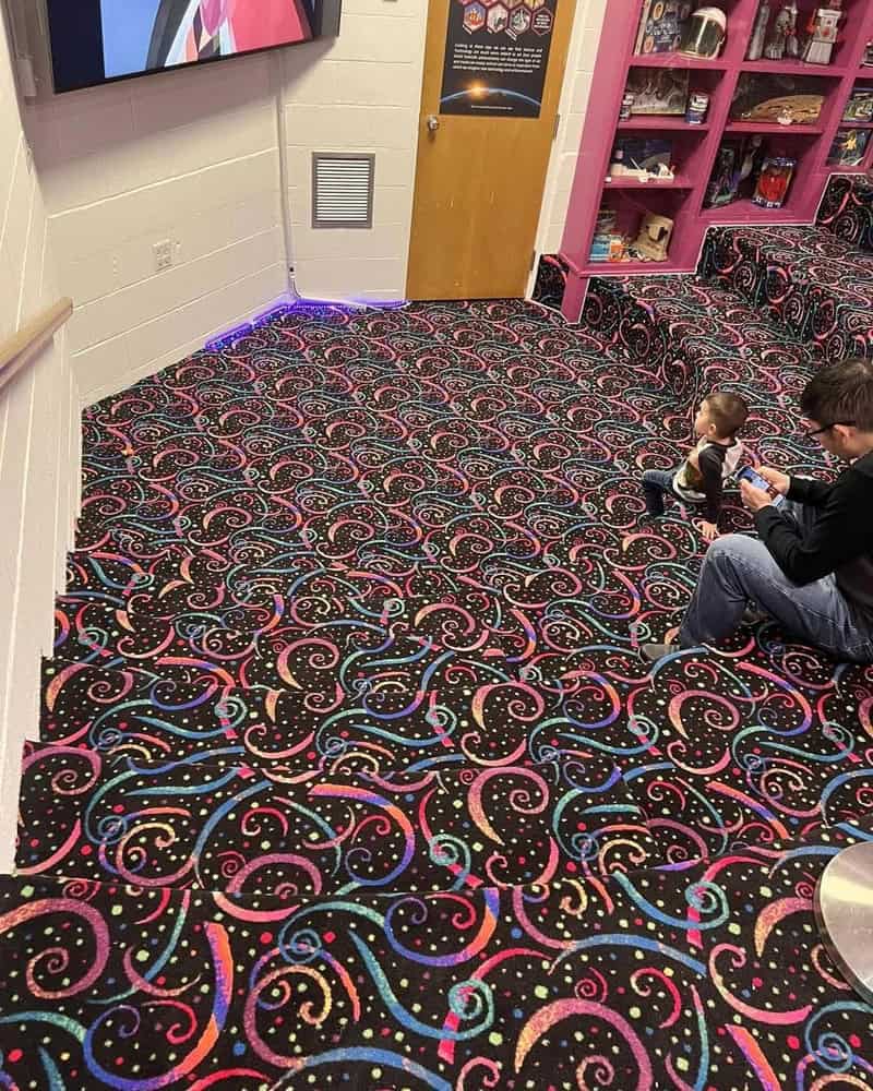 Colorful, swirling carpet in a store with two children sitting on it.