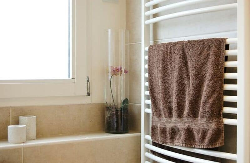 Brown towel hanging on a white heated towel rail in a bathroom.