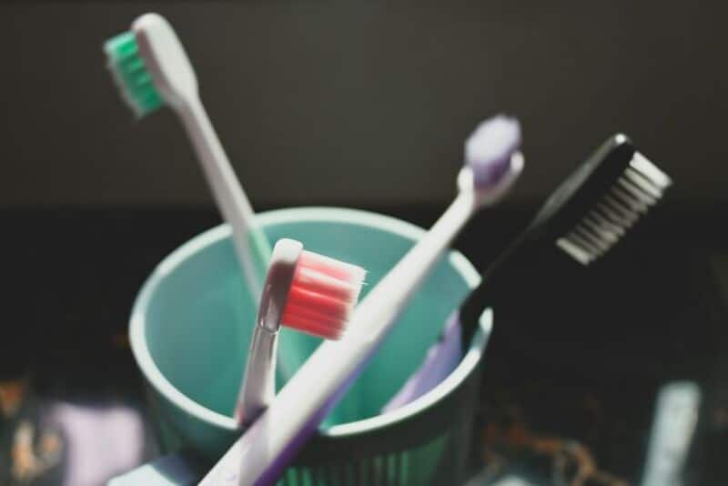 Toothbrushes in a cup with a dark background.
