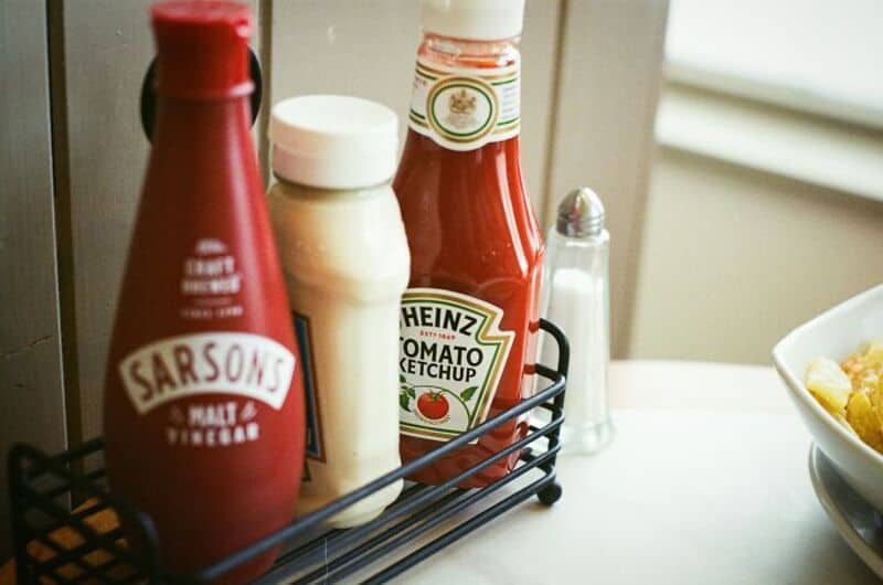 Ketchup, mayonnaise, and mustard bottles on a condiment rack.