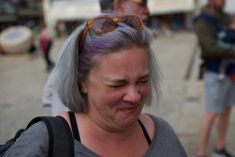 Woman crying with sunglasses on her head at an outdoor event.
