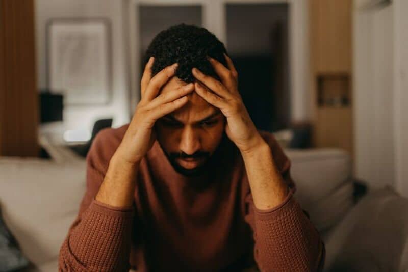 Man holding his head in frustration or stress in a living room.
