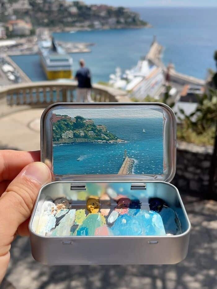 View of the harbor and coastline through a smartphone screen held in hand.