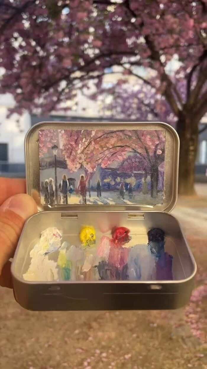 Brightly colored paint palette with a painted scene of cherry blossoms and people in the background.