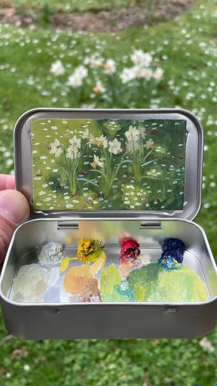 Colorful paint palette with flowers reflected in a smartphone screen outdoors.