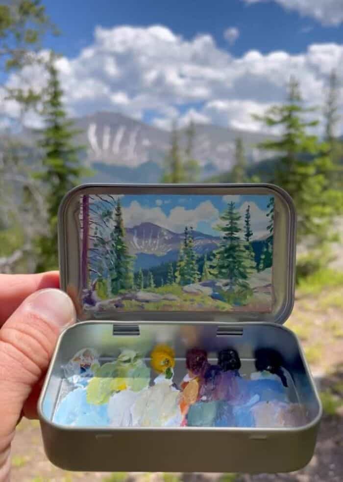 Landscape view of mountains and trees with a phone capturing the scene.