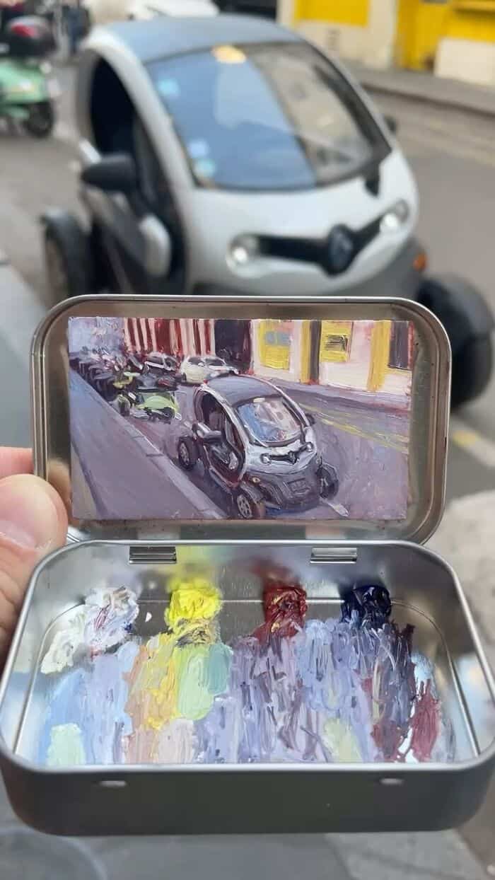 Small portable painting setup with a smartphone displaying a car scene.
