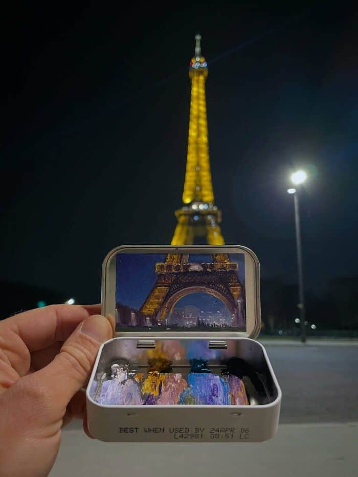 Eiffel Tower illuminated at night with a person taking a photo using a smartphone.