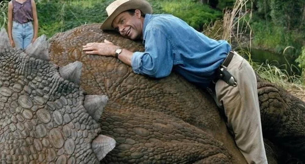 Man hugging a large crocodile in a natural outdoor setting.