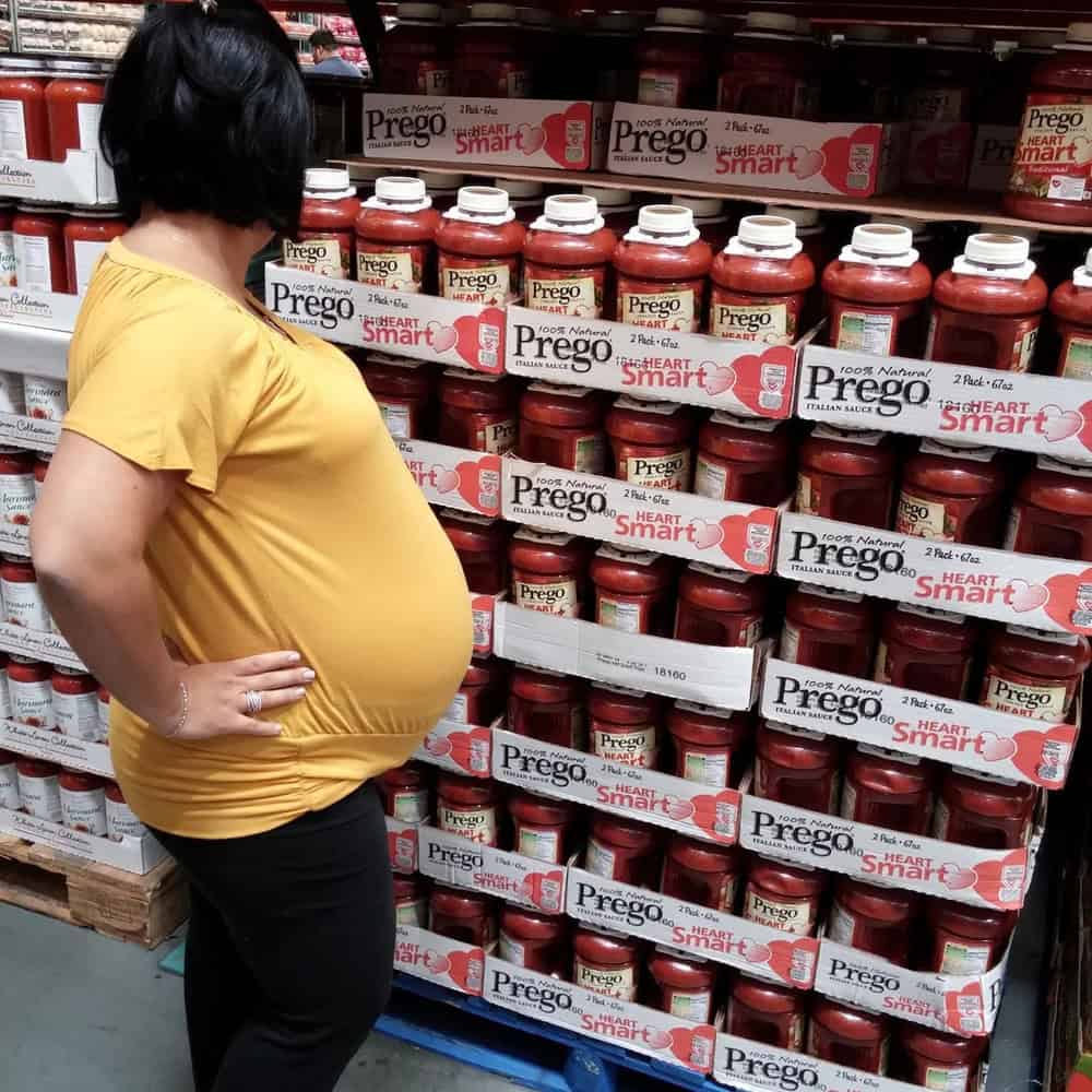 Prego Heart Smart pasta sauce jars on store shelf with pregnant woman in yellow shirt looking at the.