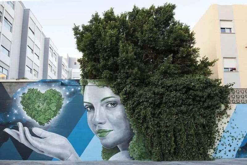 A lush green tree growing in front of a mural of a woman holding a heart-shaped plant.