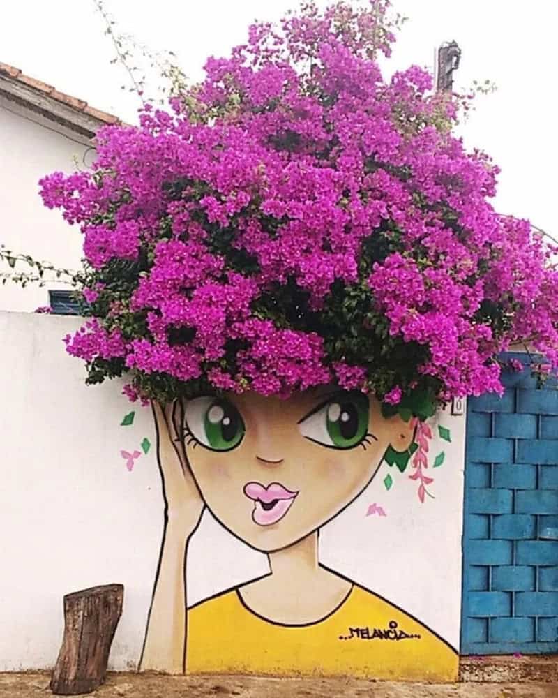 Artistic mural of a girl with a large pink flowering head in an outdoor setting.