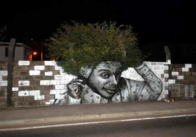 Black and white mural of a girl with a tree growing from her head on a brick wall.