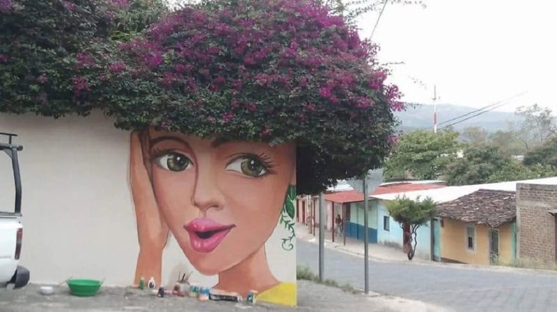 A colorful mural of a woman's face with a large floral headdress on a wall.