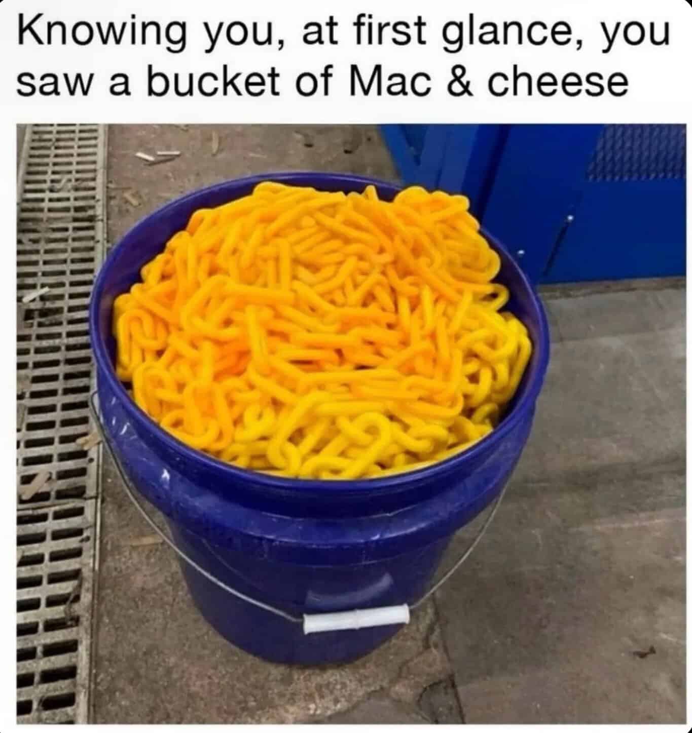 Bucket filled with yellow Mac and cheese, outdoors on concrete surface.