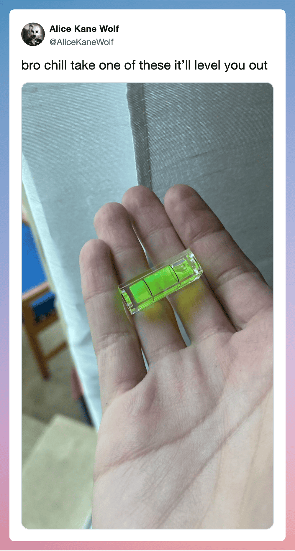 Hand holding a small green spirit level against a wall.