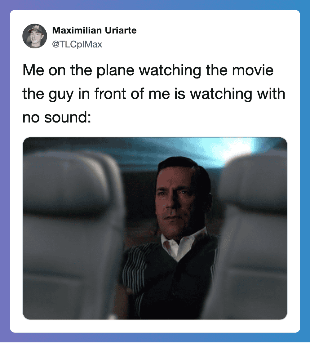 Man on plane watching a movie with no sound, looking serious.