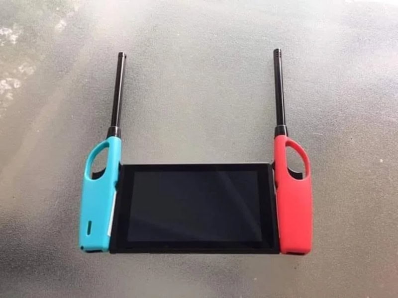 A handheld gaming console with blue and red controllers attached, placed on a gray surface.
