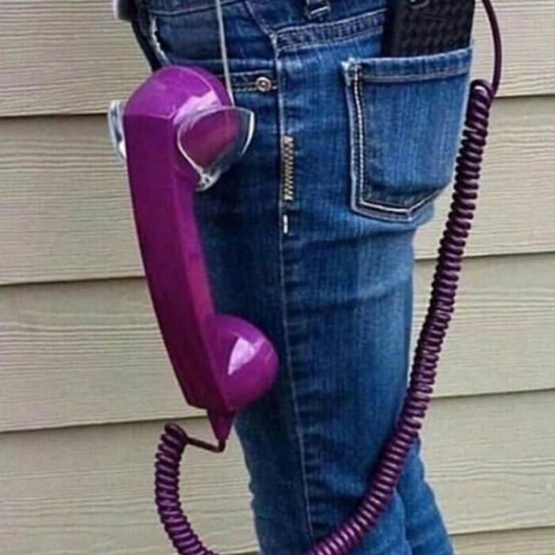 Person with a purple vintage rotary phone hanging from their pocket.