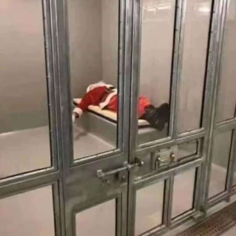 Santa Claus lying on a bed inside a metal cage.