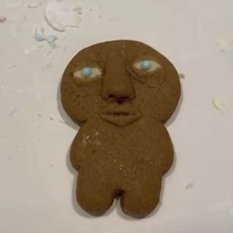 Cookie with a human face and blue eyes on a white surface.