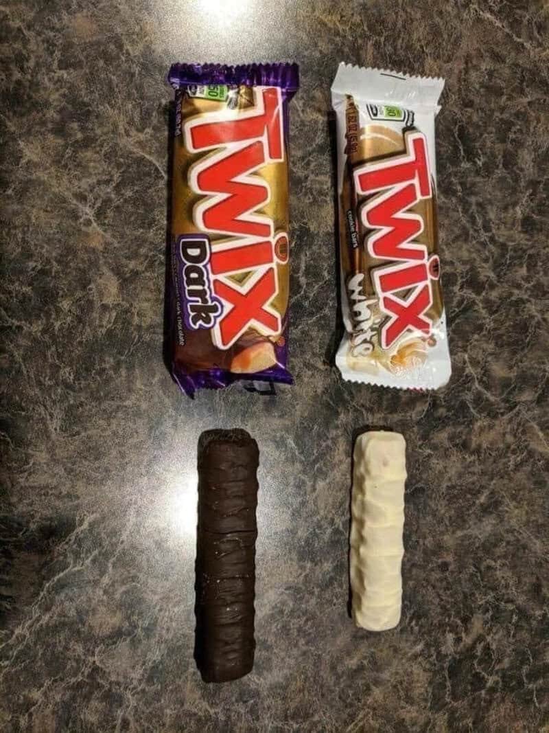 Twix chocolate bars, one in dark chocolate and one in white chocolate, placed on a dark marble surfa.