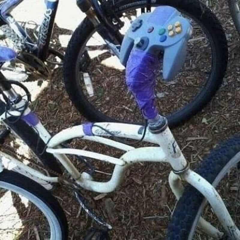 A bike with a blue gaming controller attached to the handlebar.