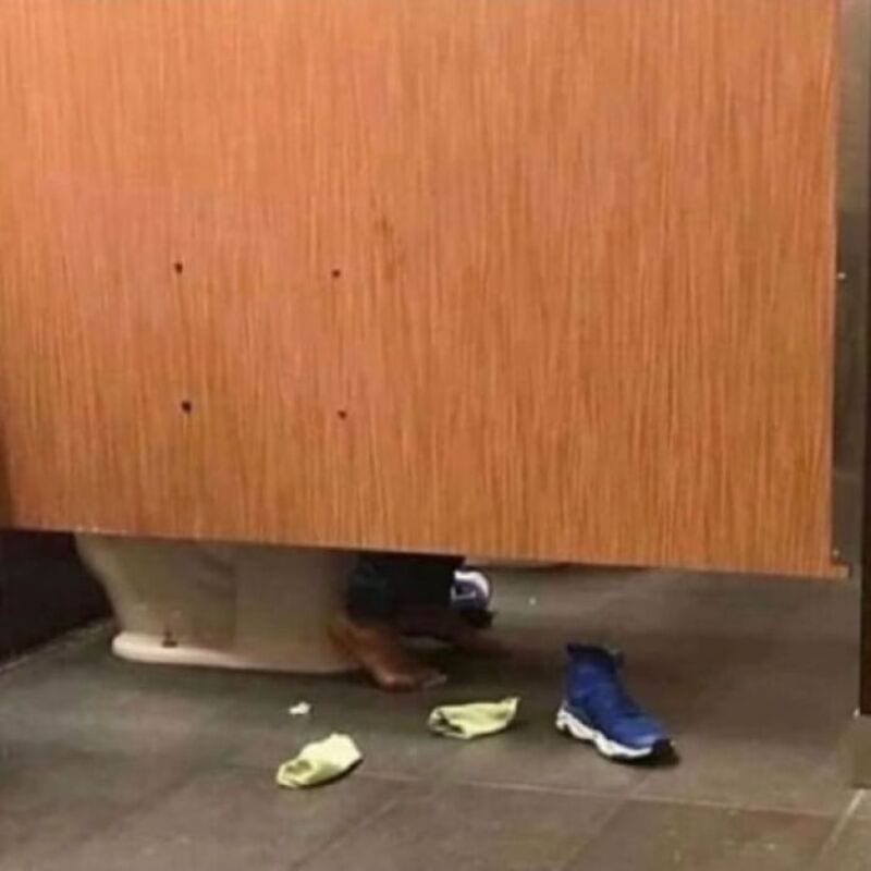 Shoes and feet visible under a wooden door, with a pair of blue sneakers and yellow slippers on the.
