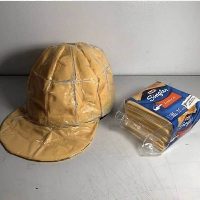 Packaged spaghetti and a crumpled paper bag resembling a hat on a gray surface.