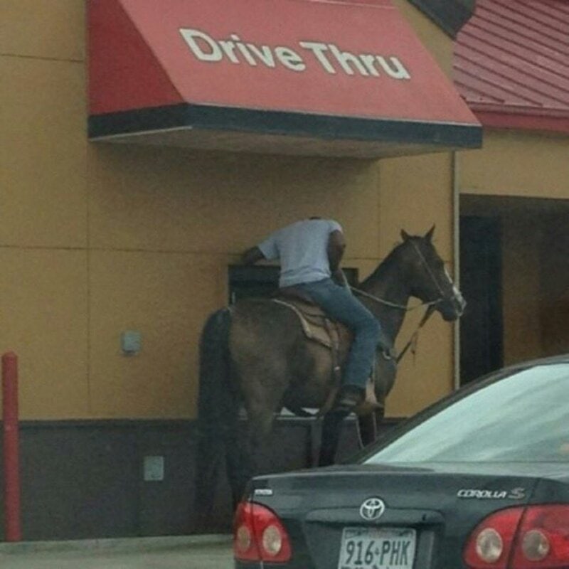 Man on horseback at drive-thru window of fast food restaurant.