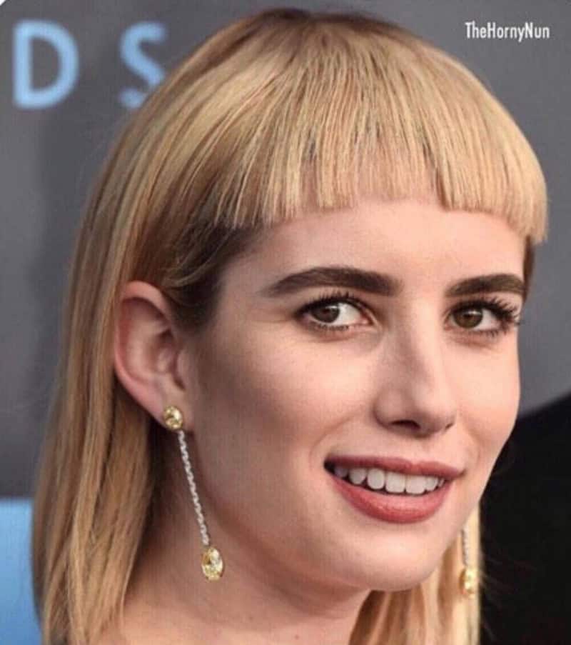 Woman with a poorly cut blonde bob and uneven bangs, smiling.