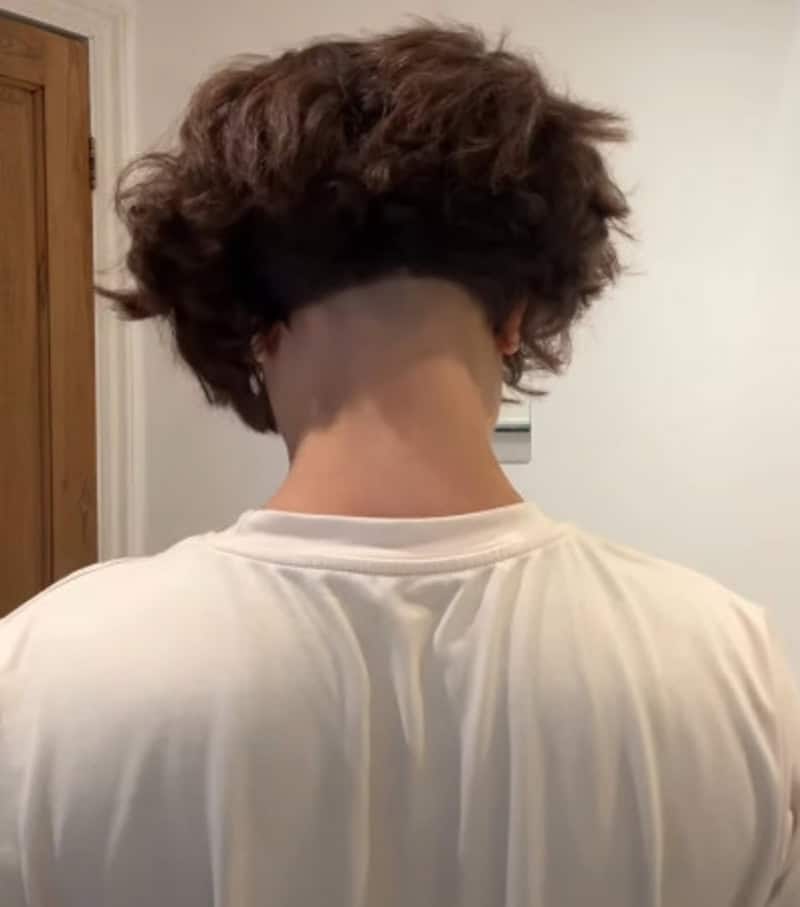 Back of person's head with uneven haircut, longer hair on top and shaved sides.