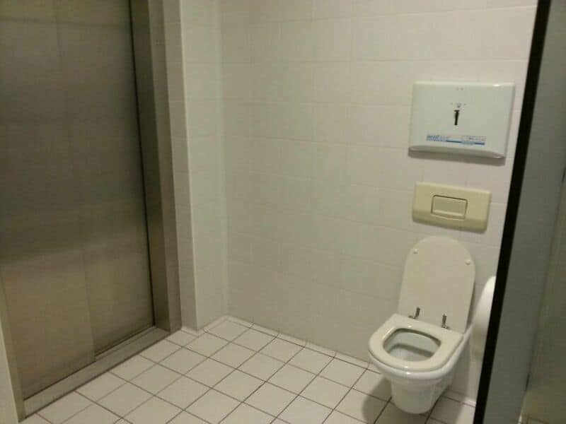 Toilet with open lid in a bathroom near an elevator door.