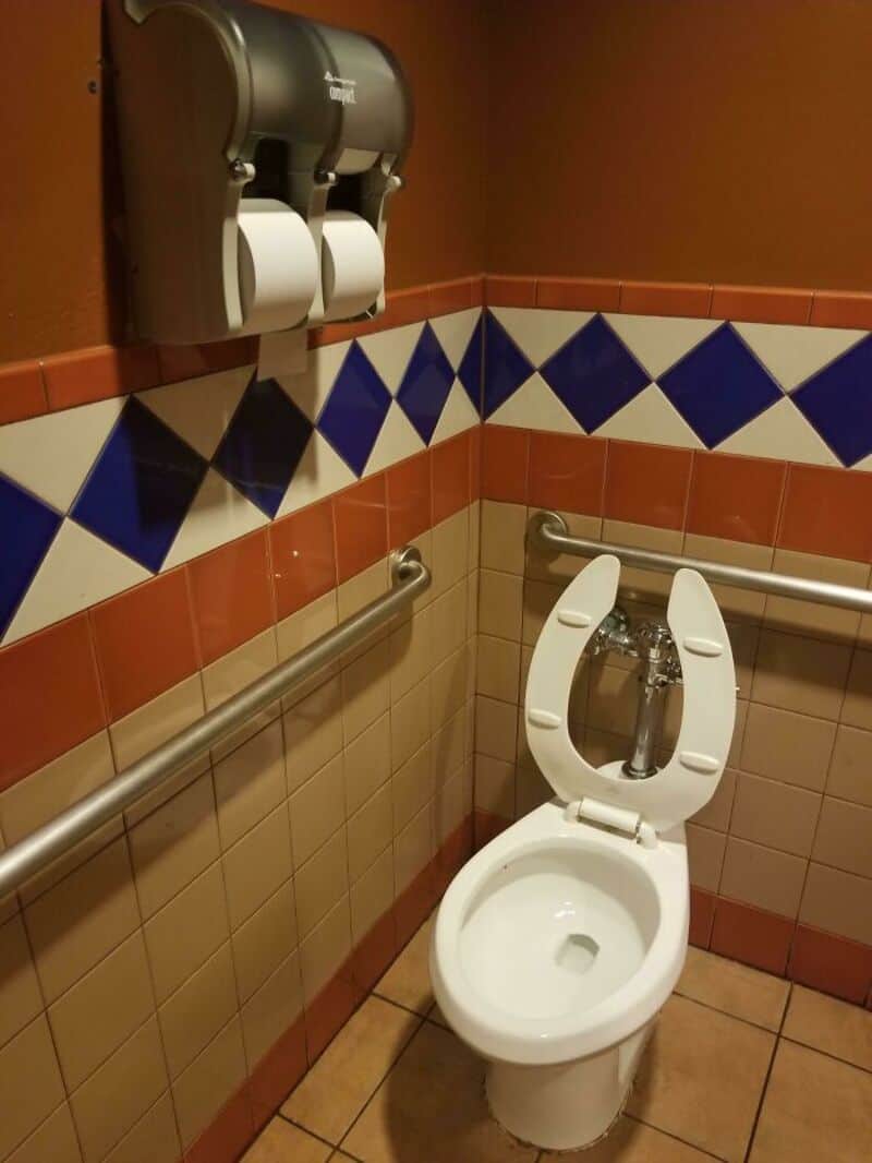 Bathroom with a toilet and a dual toilet paper dispenser on the wall.