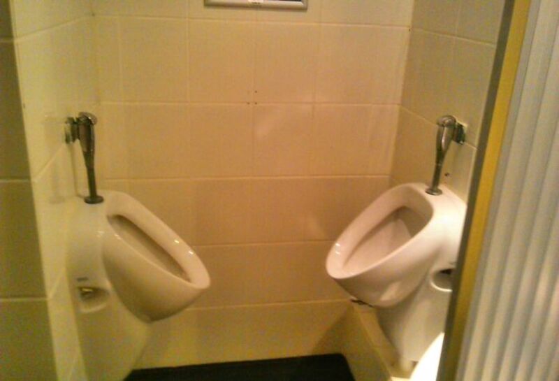 Two urinals are placed very close together in a bathroom.
