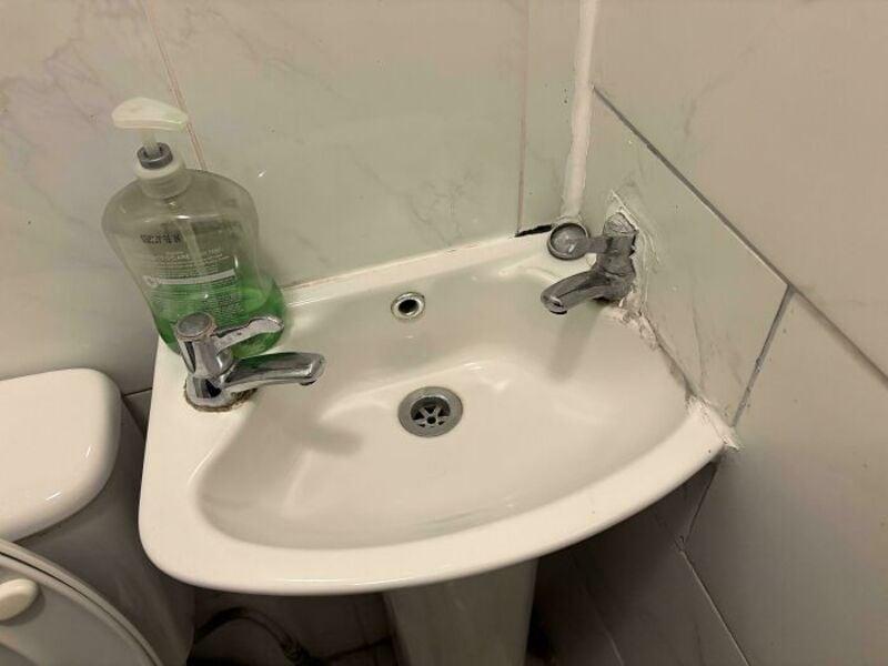 Bathroom sink with mismatched faucets and a soap dispenser on the left.
