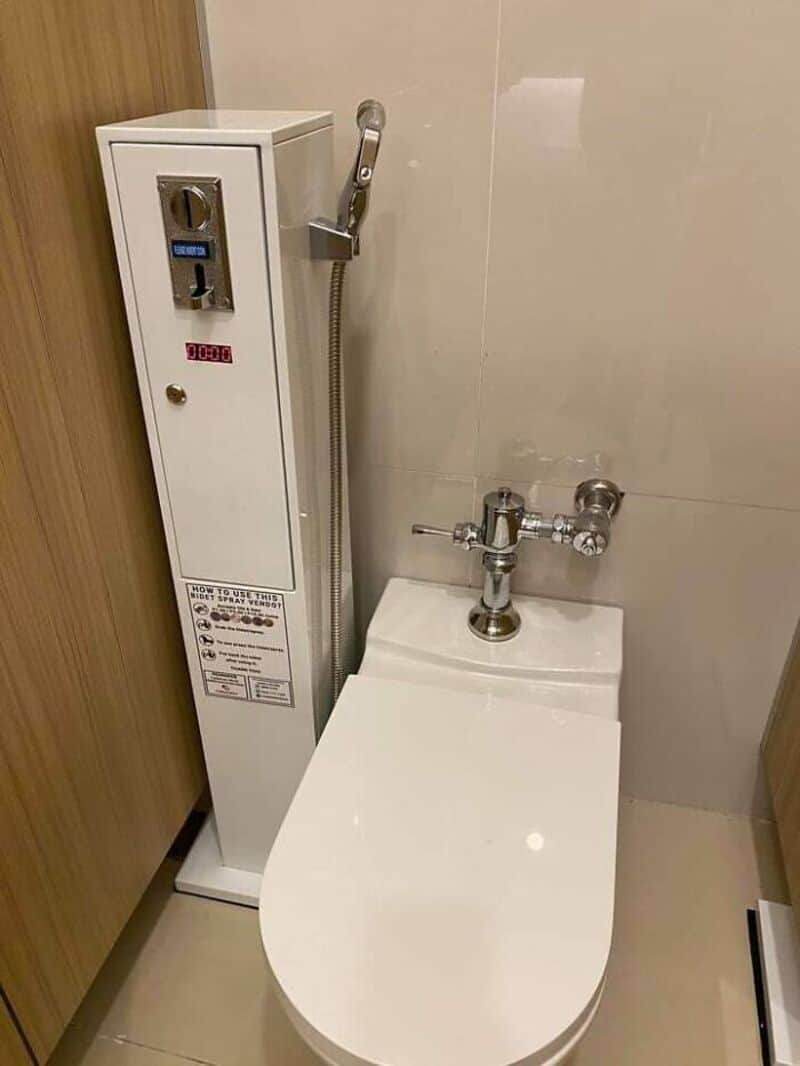 Bathroom design fail with a toilet and a water dispenser next to each other.