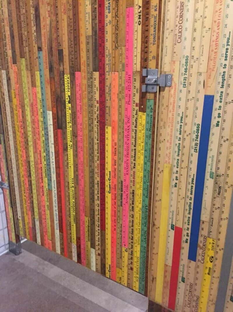 Colorful wooden door with a metal latch, covered in painted ruler markings.