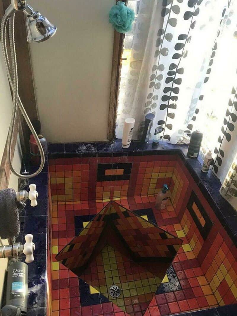 Bathroom with a mosaic bathtub and a mirror, curtain, and toiletries.