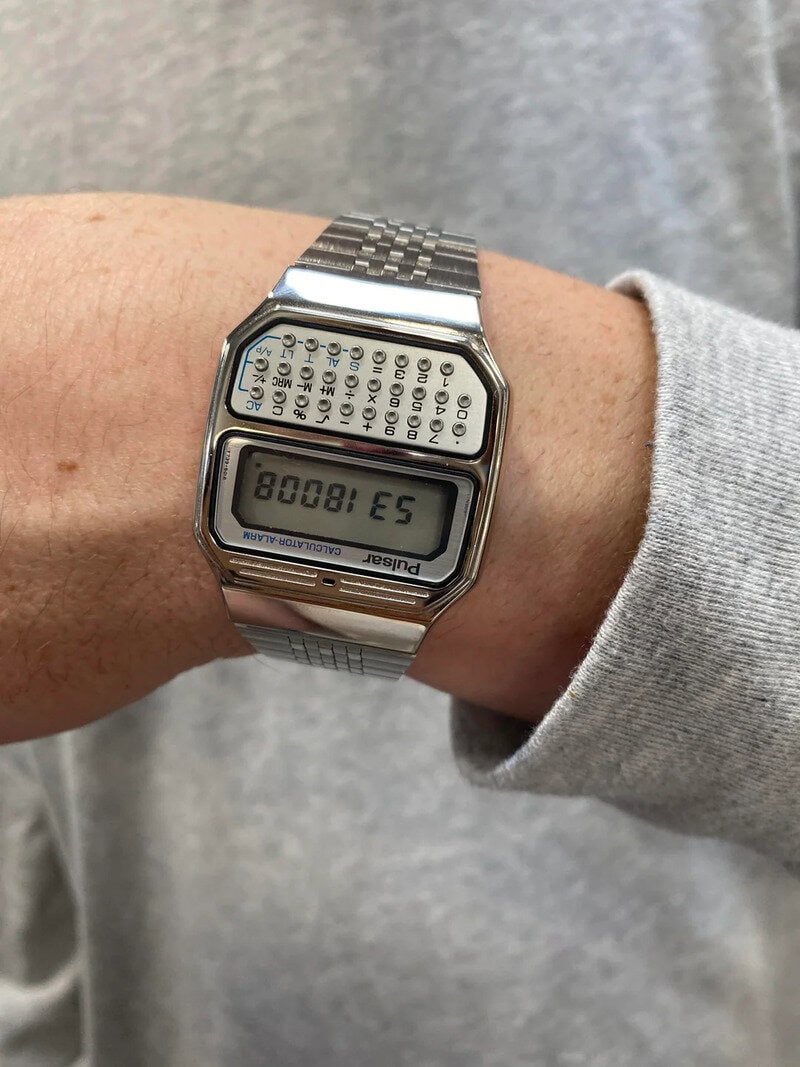 Digital calculator watch displaying "ES 1800" on the screen.
