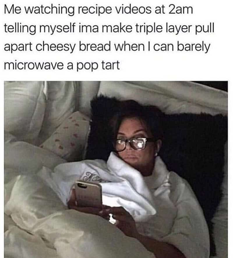 Relaxed woman watching recipe videos on her phone in bed at 2am, planning to make a cheesy bread.