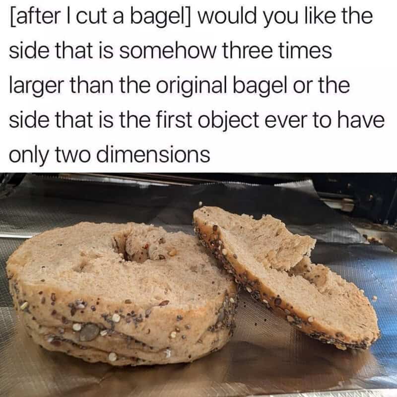 Bagel with a larger, thicker side slice placed next to it on a reflective surface.