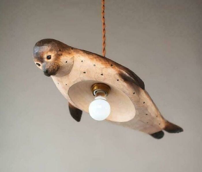 Light fixture designed as a bird with a light bulb as its body, hanging from a twisted cord.