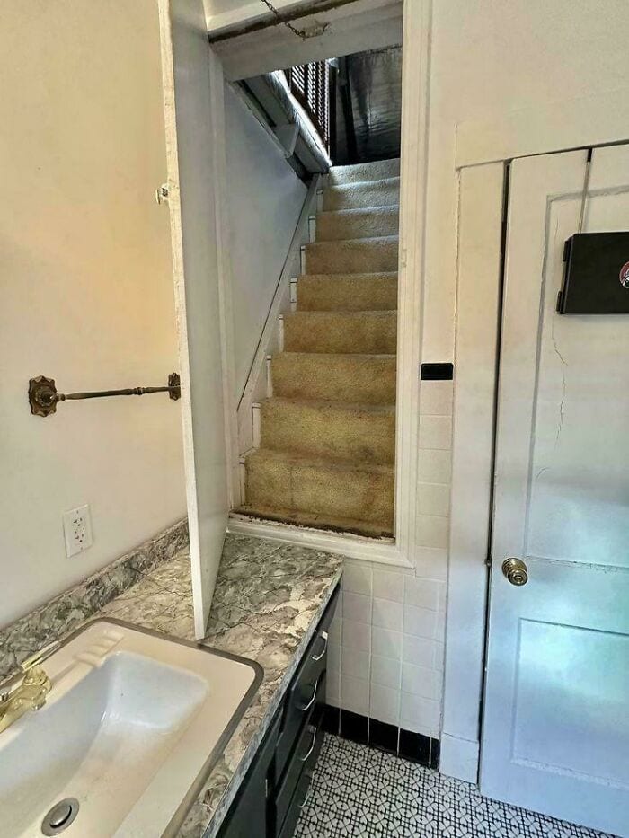 Narrow staircase seen from kitchen with door open at bottom.