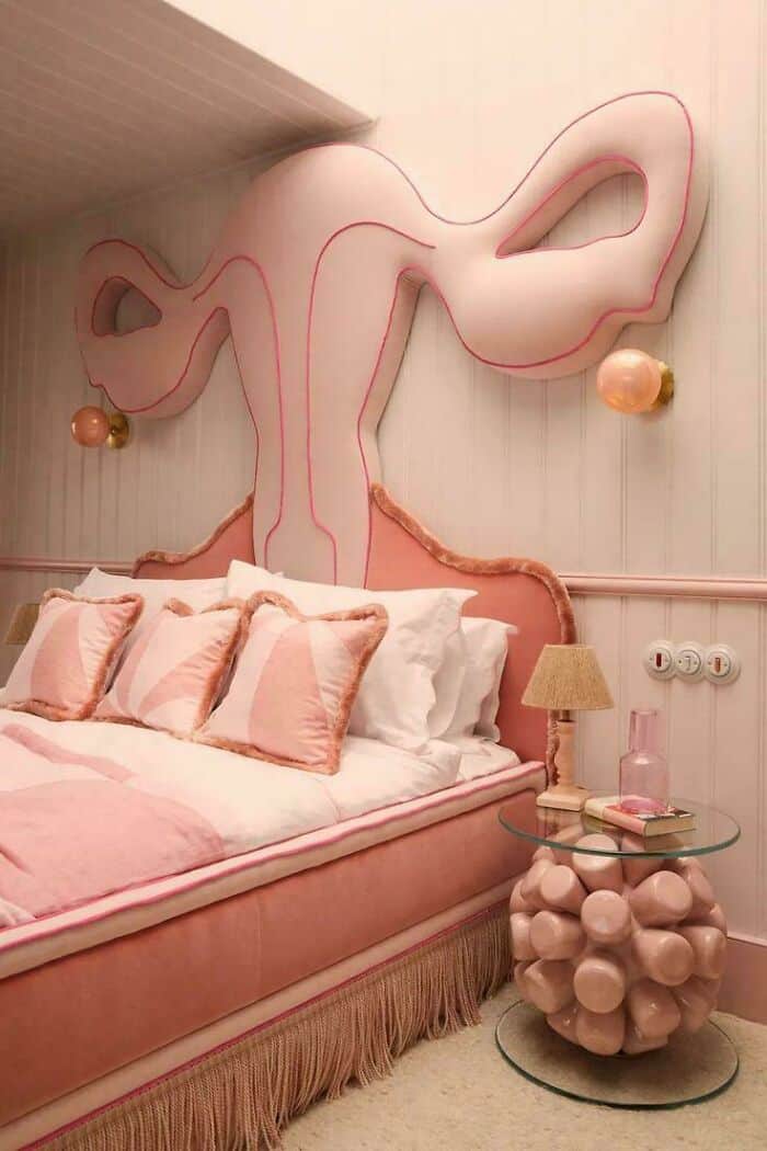 Whimsical pink headboard with abstract design above a cozy bed with pillows.