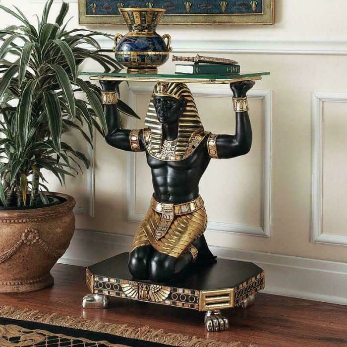 Egyptian-style black and gold statue of a man holding a tray with a vase and a sword.