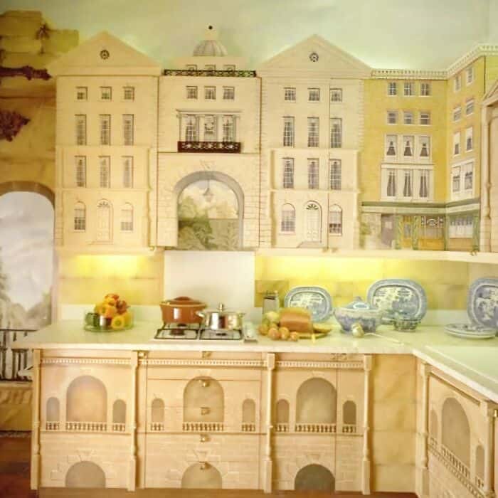 Miniature kitchen with a castle backdrop and vintage dishes.